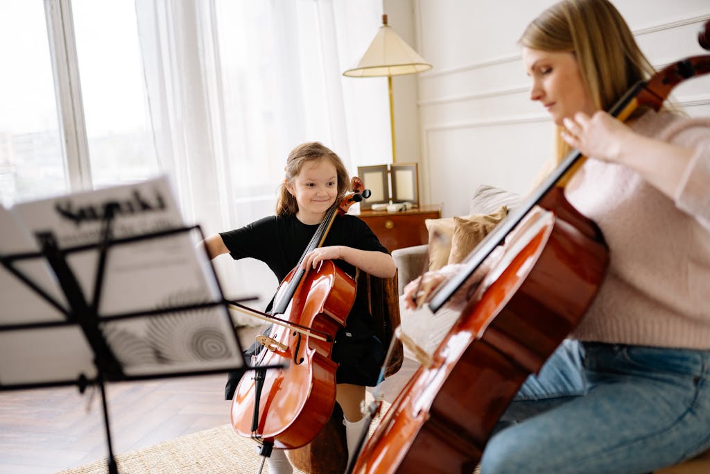 A mother teaching her daughter how to play the cello in a cozy living room setting.